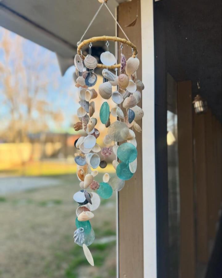 Natural seashell and aqua sea glass wind chime hanging outdoors by @texas_sunshine12 showcasing seashell crafts for adults with beach-inspired materials.