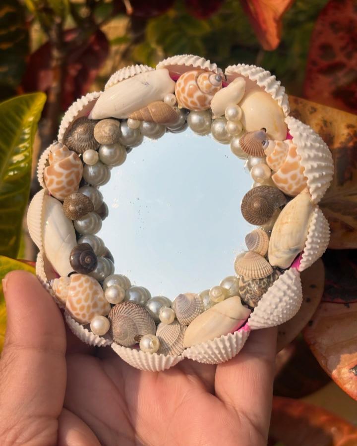 White and beige seashell mirror frame with pearl beads by @rupa__ghosh__. A delicate and natural seashell crafts for adults project.