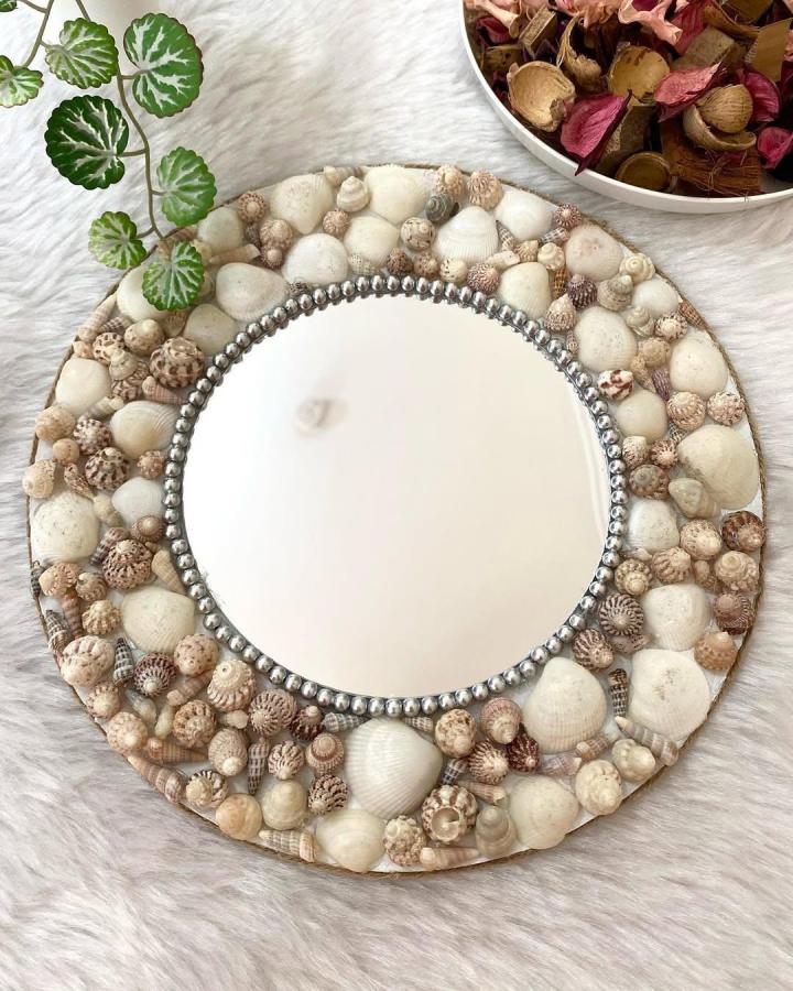 White and beige seashell mirror frame from @_mimi_suki_ featuring natural tones and silver bead accents in seashell crafts for adults.