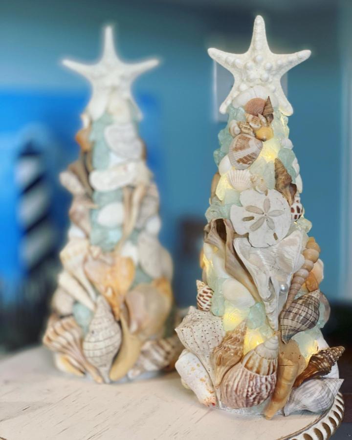Seashell and starfish decorated cone tree with sea glass accents and warm white lights by @enchantedtidetrees coastal-inspired craft.