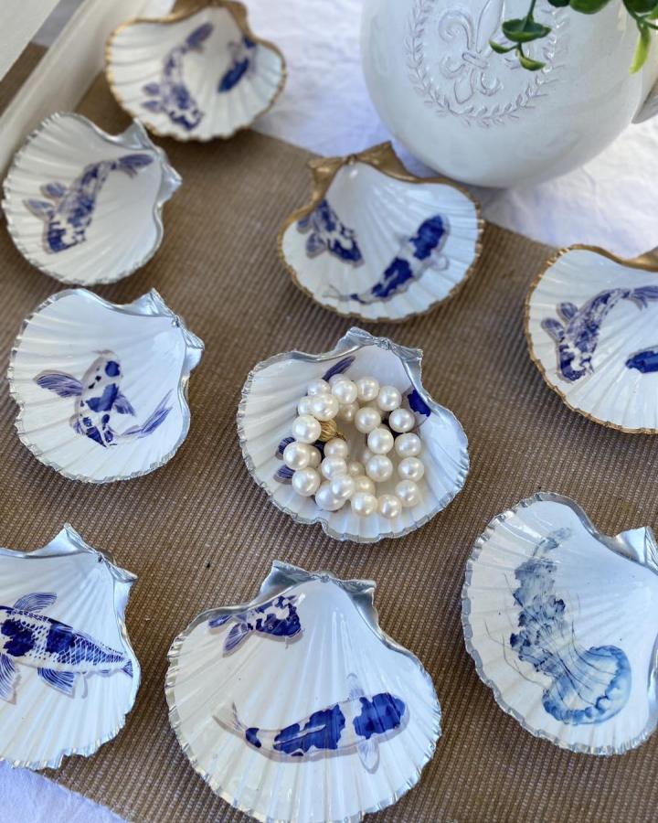 White scallop shells painted with blue fish designs and silver or gold edges for summer crafts for adults jewelry dishes by @glamptonshells.