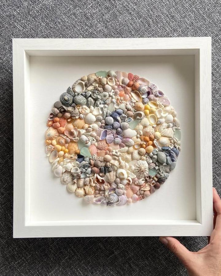 Seashell mosaic art in pastel colors framed in white, perfect for warm weather creative projects.