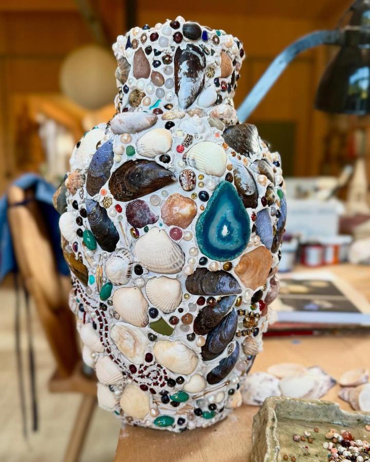 Seashell and bead mosaic vase with teal agate centerpiece on wooden table by @natalie_lete summer coastal craft decor.