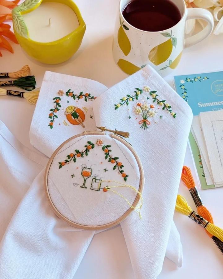 Bright orange and green embroidered summer motifs on white linen with floral and citrus designs by @talesfromthehoop perfect for warm season crafting inspiration.