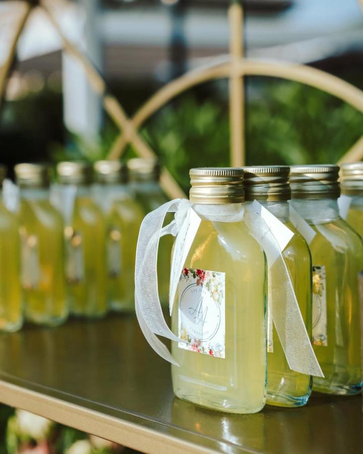 small clear glass limoncello bottles with gold caps and white ribbons by @marypiras_events wedding favor ideas bright and refreshing display on gold tray