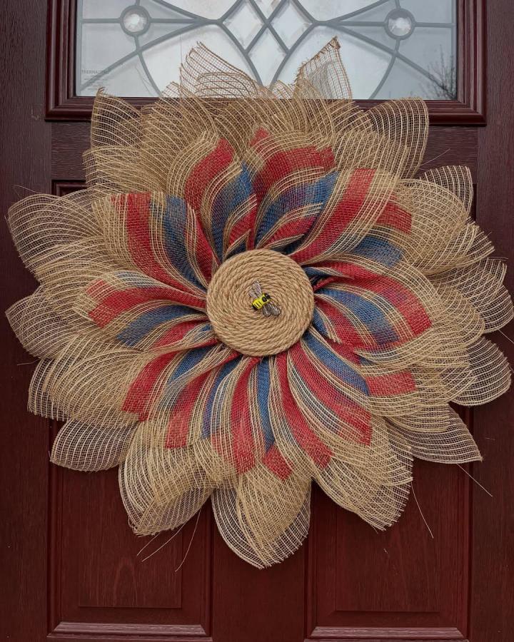 Natural striped burlap flower wreath from @thevinecottages on dark wooden door with rope bee centerpiece. Rustic and colorful.