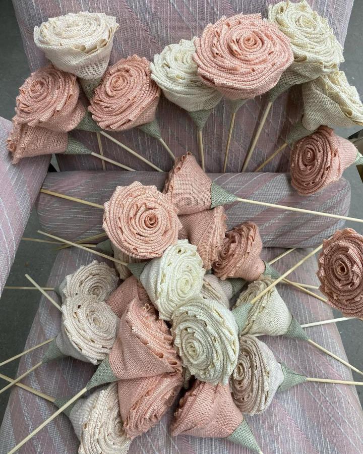 Soft blush and cream handmade burlap floral stems from @saatlanticave. Rustic rose petals on sticks arranged on fabric chair.