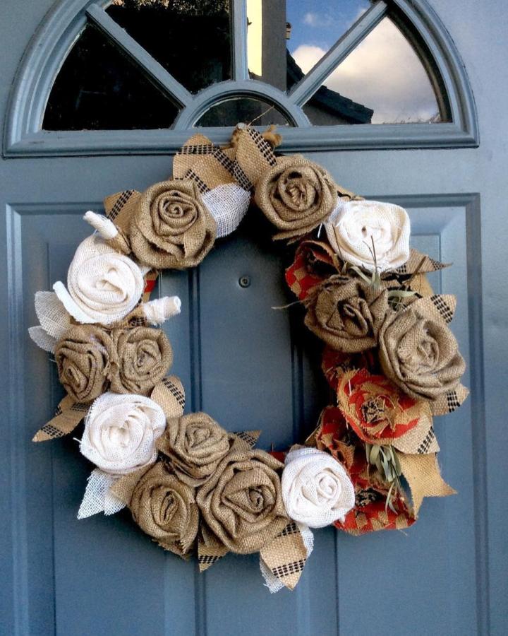 Rustic burlap rose wreath with checkered leaves and red fabric accents from @rosalindclarkeart. Front door craft decoration.