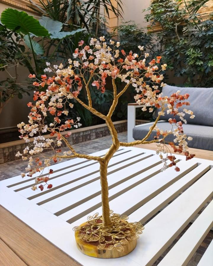 Copper wire tree sculpture with peach and clear beads on wooden base by @eiradesigns_ showing delicate hand-twisted branches and sparkling details