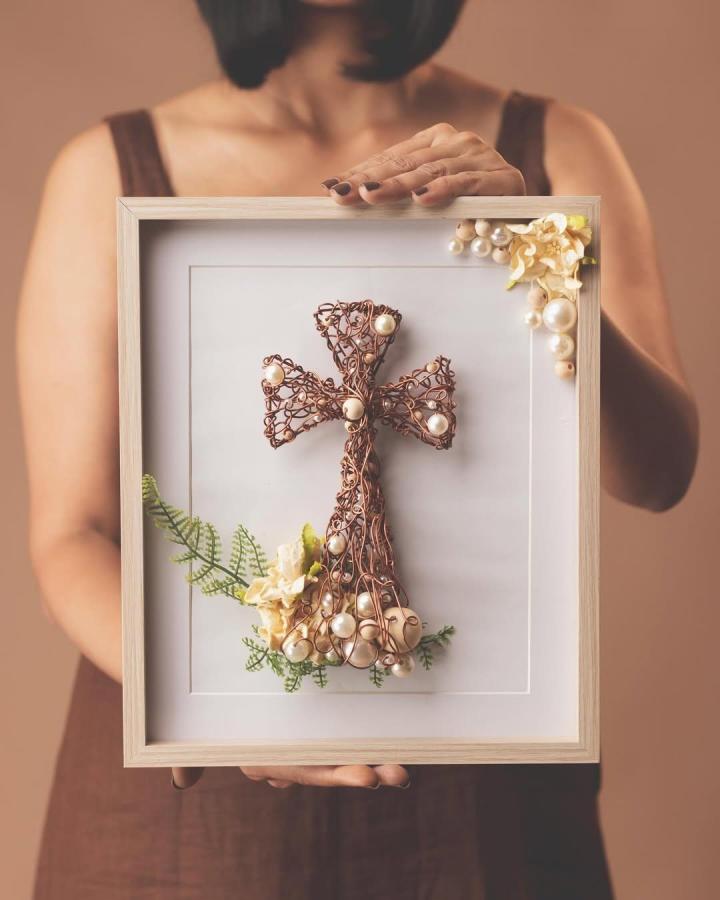 Copper wire cross framed art from @beautyforashes_by_nez. Detailed wirework accented with pearls and floral touches.