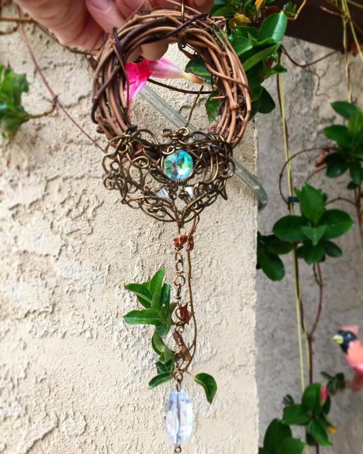 Warm copper wire wrapped crystal wall hanging with natural twig frame and green vine accents from @spiritlunar. Unique handmade decor piece.