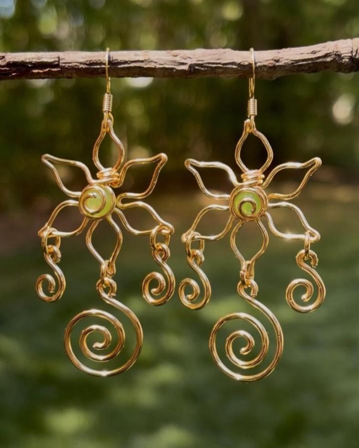 Copper wire crafts flower earrings with spirals and green bead accents from @getstonedbyamber hanging on a natural twig.