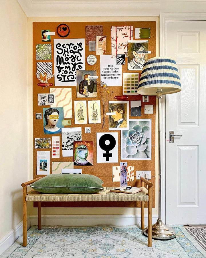 Rustic cork wall collage in a cozy corner from @thepajaamahub featuring diverse art and prints with a green velvet pillow.