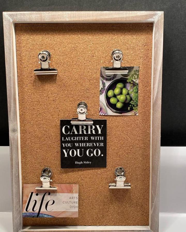 Farmhouse cork board with whitewashed frame and silver clips from @z9designs displaying notes and photos. Rustic and functional.