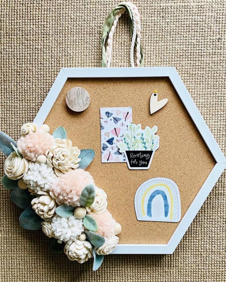 Hexagon white-framed cork board with blush pom-poms and floral decorations by @stsorlinstreet perfect for home organizing and decorating.