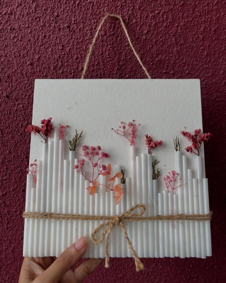 White straws and delicate dried flowers craft wall art with twine bow by @__our_journal__. Textured dried flower crafts with natural charm.