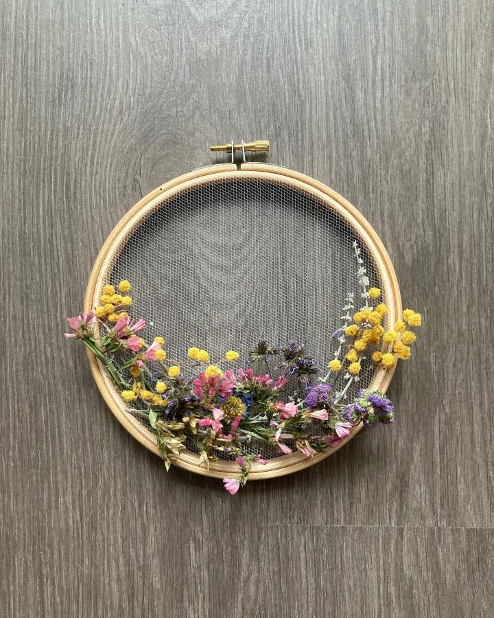 Yellow pink and purple dried flowers arranged on wooden embroidery hoop with mesh netting from @brillil. Stylish dried flower crafts decor piece.