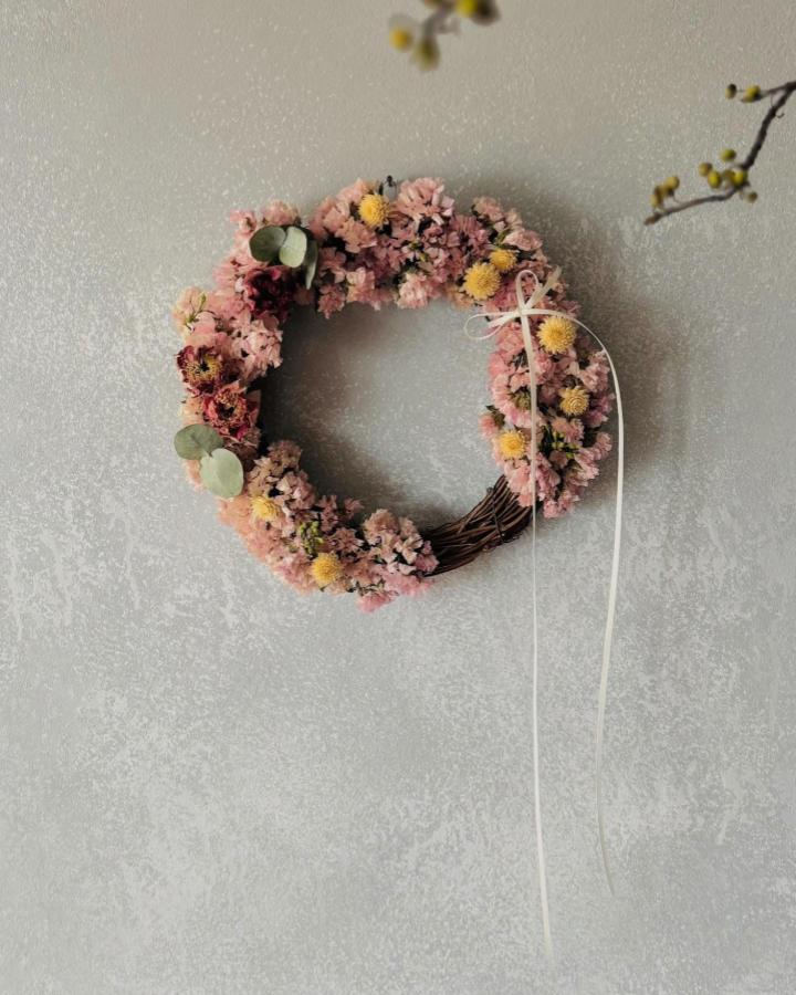 Pink and yellow floral wreath with eucalyptus on twig base wall hanging by @berry.homebk. Soft and rustic textured floral decor.