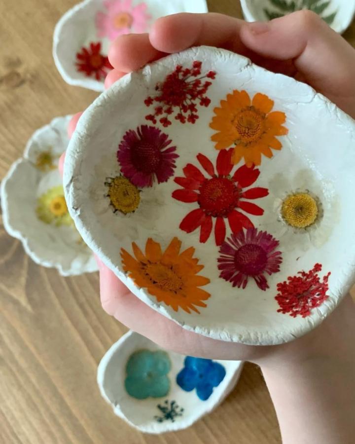 Bright handmade clay trinket bowls featuring colorful pressed flowers from @charlotte_and_the_boys. Rustic and charming craft detail.