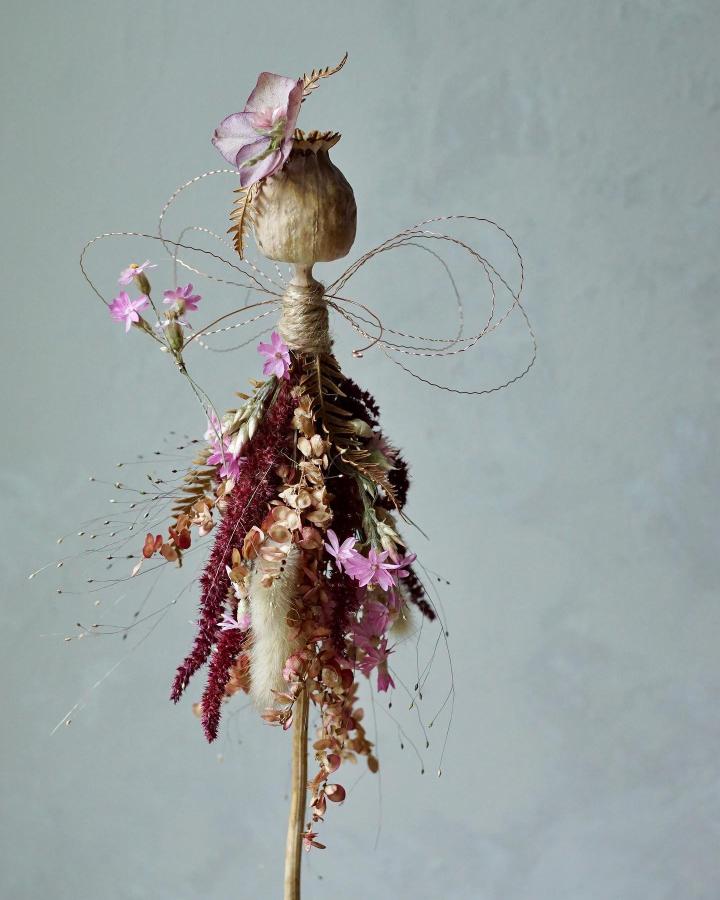 Dried flower fairy with poppy pod head and burgundy-pink floral skirt from @harebellandbee, delicate handmade natural craft.
