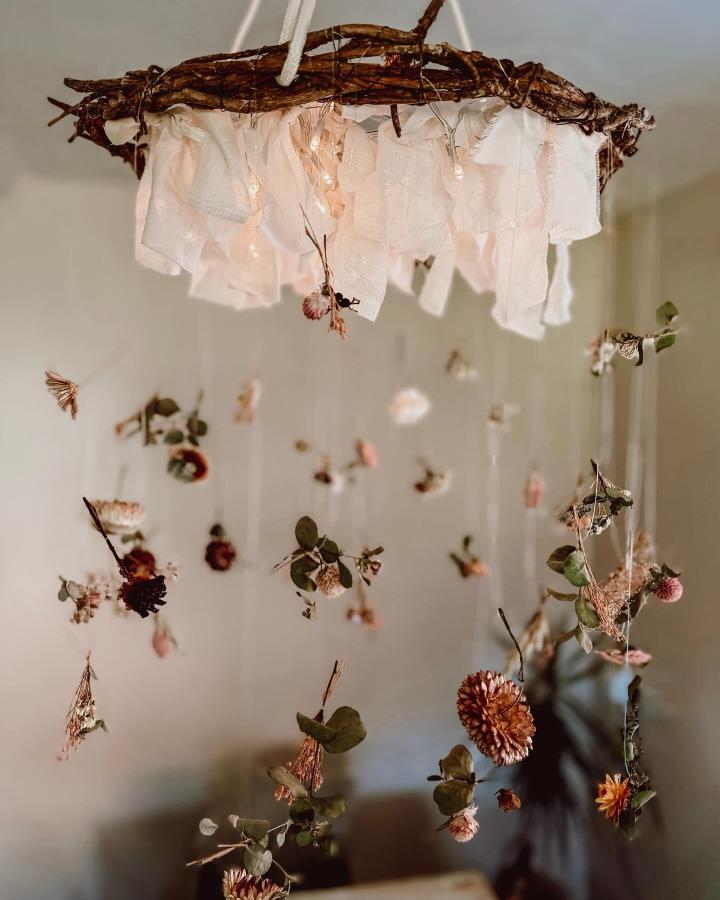 Neutral rustic floral mobile with soft fabric pieces from @along_the_country_lane. Hanging dried wildflowers float gently in a cozy home setting.