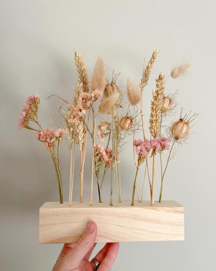 Soft pastel dried flowers in wooden block from @foxtail_floral_design. Minimalist floral bar arrangement with wheat and bunny tails.