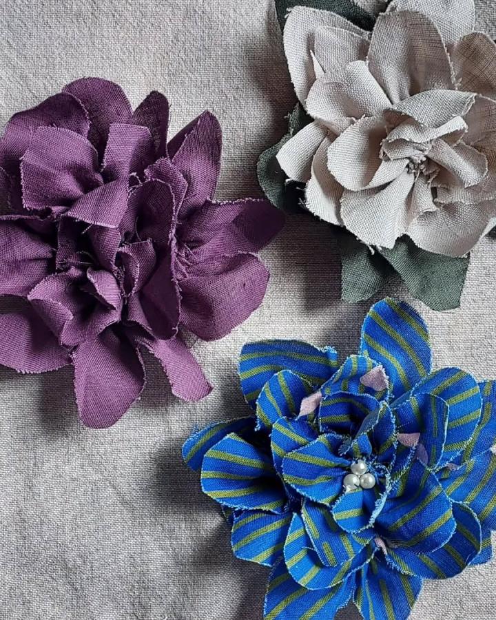 Purple, beige, and blue striped fabric flowers showcasing layered petals and pearl accents from @robyn.quilts as fabric flower ideas.