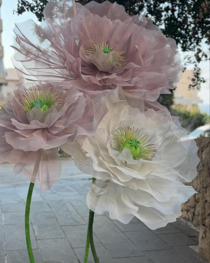 Sheer oversized blush and white fabric flowers with bright green centers on flexible stems by @blooms_by_yara outdoors. Soft translucent petals highlight delicate handmade blooms.