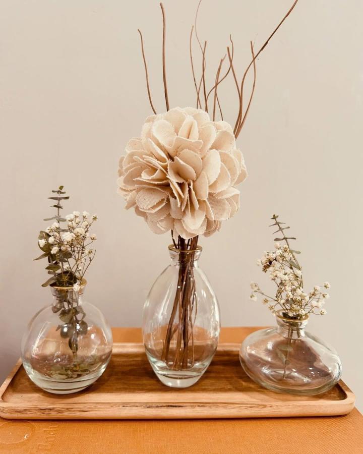 Neutral beige cotton flower with dried twigs and eucalyptus in glass vases from @suzi_yasu. Soft and rustic handmade floral display.