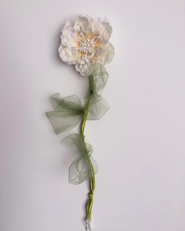 Creamy white fabric flower with pearl center and olive green tulle stem from @ildiko._.sz showcasing elegant fabric flower ideas.