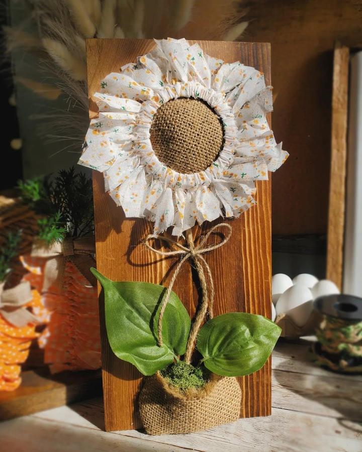 Rustic sunflower craft with burlap center and soft cream floral petals on wooden base from @lovecrafteddecor. Textured and handmade flower display.