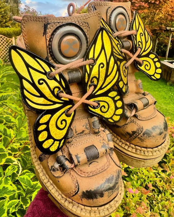 Yellow and black faux leather butterfly boot wings attached to rugged boots by @skttheshop showcasing unique faux leather crafts. Bright, bold accessory detail.
