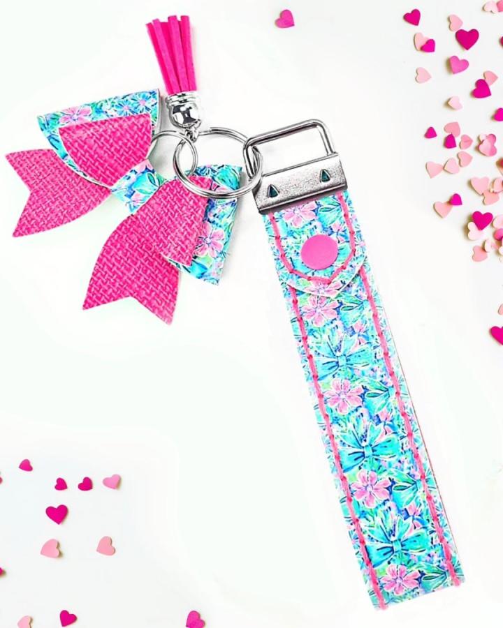 Bright pink and floral patterned faux leather keychain from @maisiemoodesign. Vibrant handmade faux leather crafts with tassels and fish-tail charms.