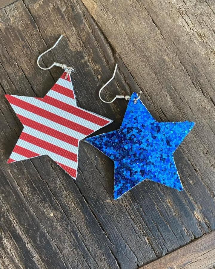 Red and white striped and blue glitter star-shaped faux leather earrings on wood background from @suede_and_oak showcasing faux leather crafts.