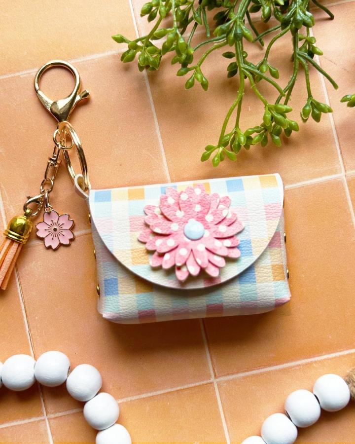 Pastel plaid and pink flower keychain charm made from textured vegan leather with gold hardware by @amyromeucrafts on peach tile background.