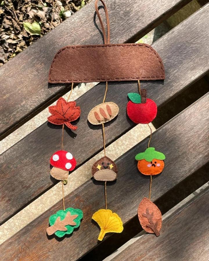 Brown and red felt autumn mobile from @longancraft featuring fall leaves, mushrooms, and fruit shapes on strings.