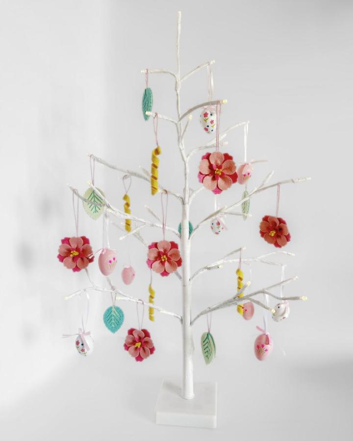 Pink and red felt flower ornaments hanging on a white decorative tree stand by @thehandmadeflorist delicate handcrafted textile décor.
