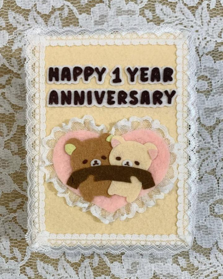 Cream, pink, and brown felt scrapbook card from @maefeltcute showing two hugging bears and lace trim celebrating an anniversary.