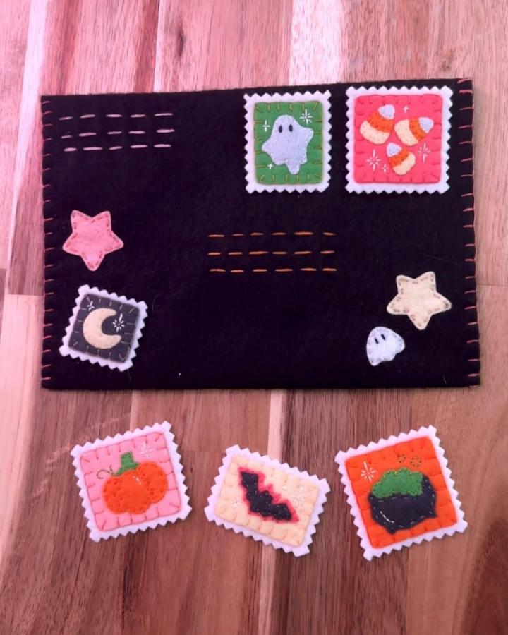 Black felt Halloween-themed iron-on patches and stamps crafted with colorful wool felt by @mariahs_makes showing tiny stitched ghosts and pumpkins.