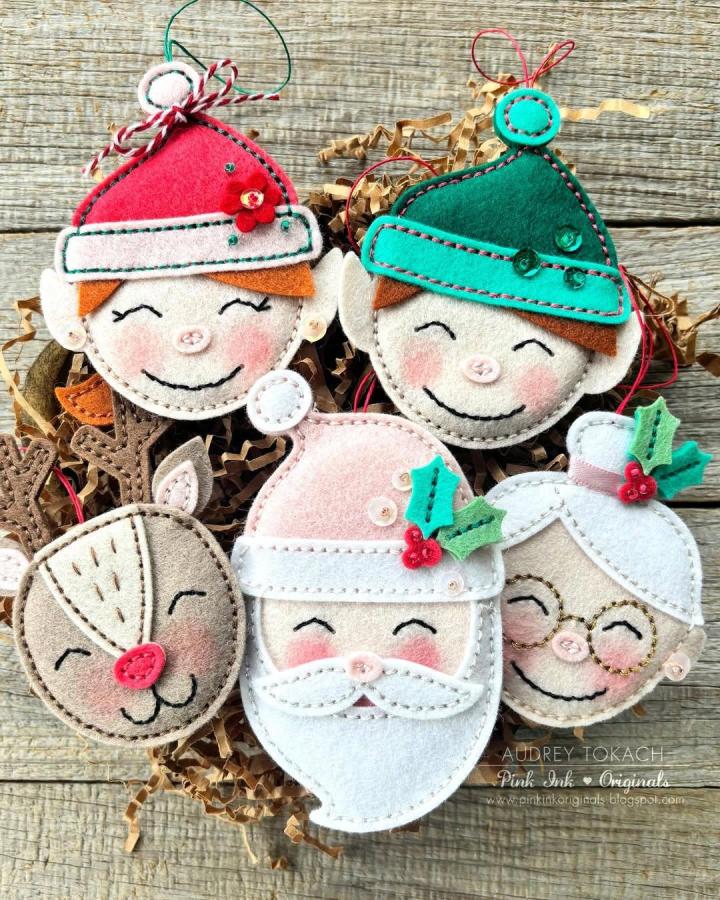 Red green and white felt handmade holiday ornaments by @audrey_tokach featuring stitched smiling elves Santa and reindeer faces.
