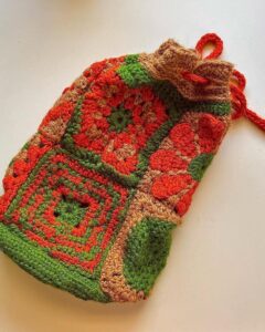 Bright green burnt orange and brown granny square crochet bag from @the.disco.loop featuring a funky autumn color mix and drawstring closure.