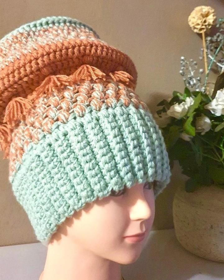 Mint green and terracotta chunky crochet hat with tassels by @yarngonewild_yarncraft showing playful texture and color blocking.