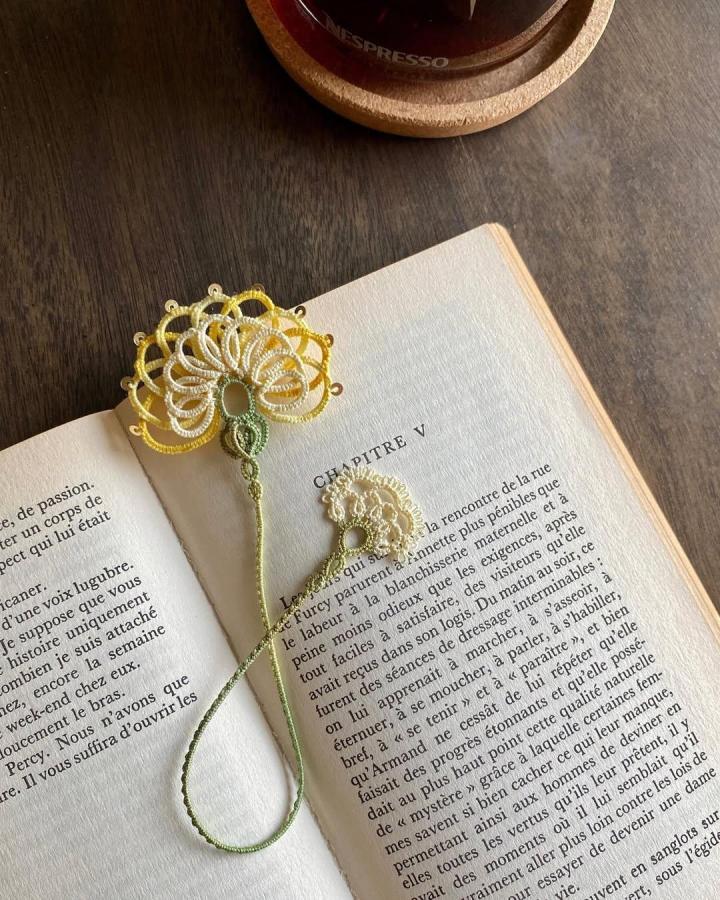 Cream and yellow tatted lace flower bookmark on open book from @forgetmeknotto. Intricate, fine cotton thread lacework accessory.