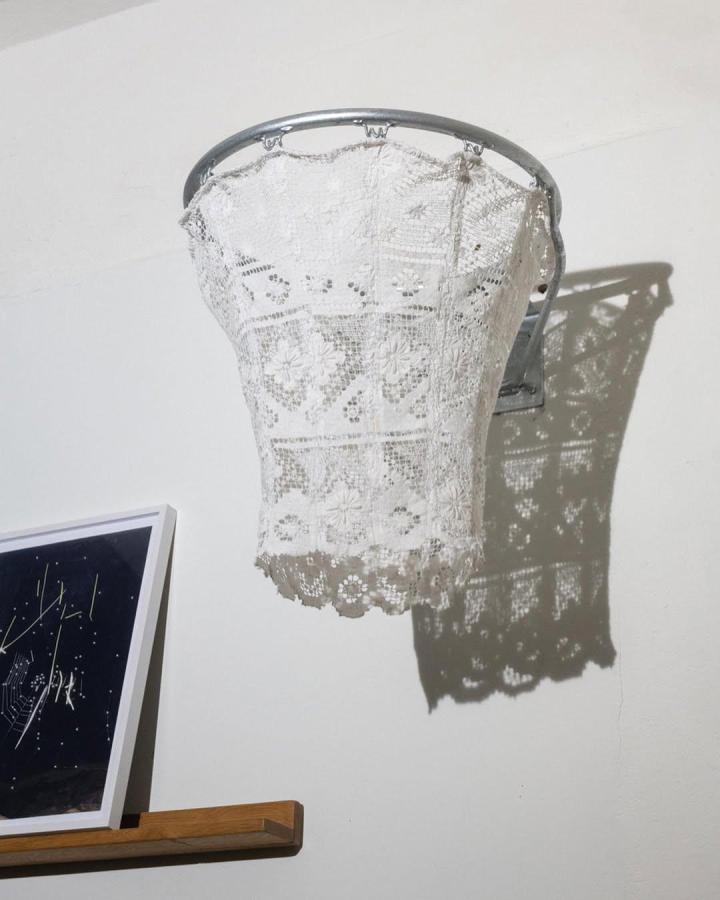 White vintage lace hoop wall sculpture decor from @sarahillenberger. Intricate floral lace patterns inside metal hoop casting delicate shadows on wall.