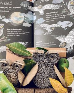 Neutral recycled cardboard owl sculptures with twigs and leaves by @indanurfarida. Detailed spiral coils form eyes and body in natural tones.