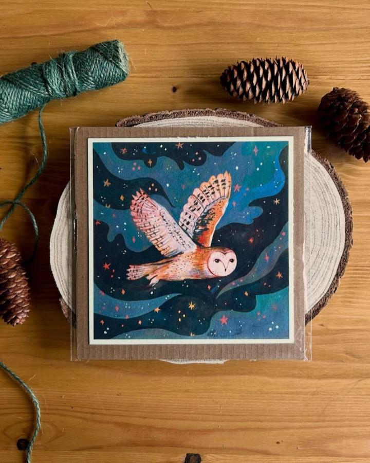 Vibrant blue and orange owl illustration on wood slice by @victoriaosorioillustration showing a starry night flight scene.