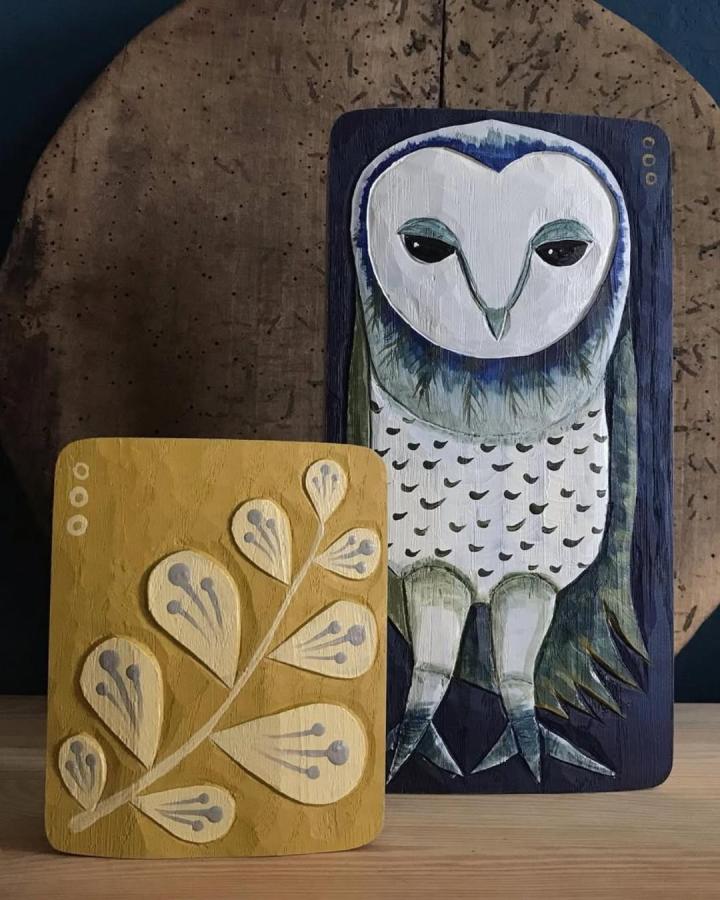 Hand-painted navy and mustard wooden owl crafts for adults from @leschiwelt featuring detailed feather and botanical designs.