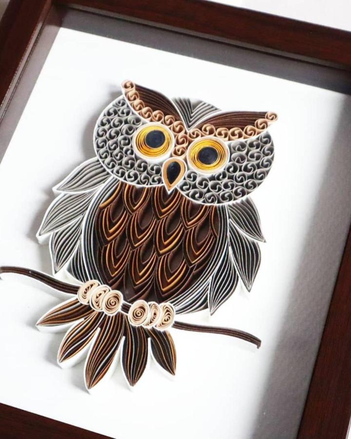 Brown and beige paper quilled owl artwork by @rawatcraft showing detailed feather curls and branch perch craft.