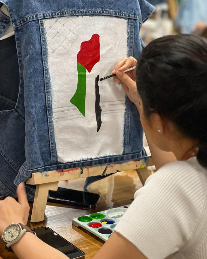 Red green and black painted denim jacket with fabric patch from @bartega.studio showing vibrant wearable art and acrylic paint craft technique.