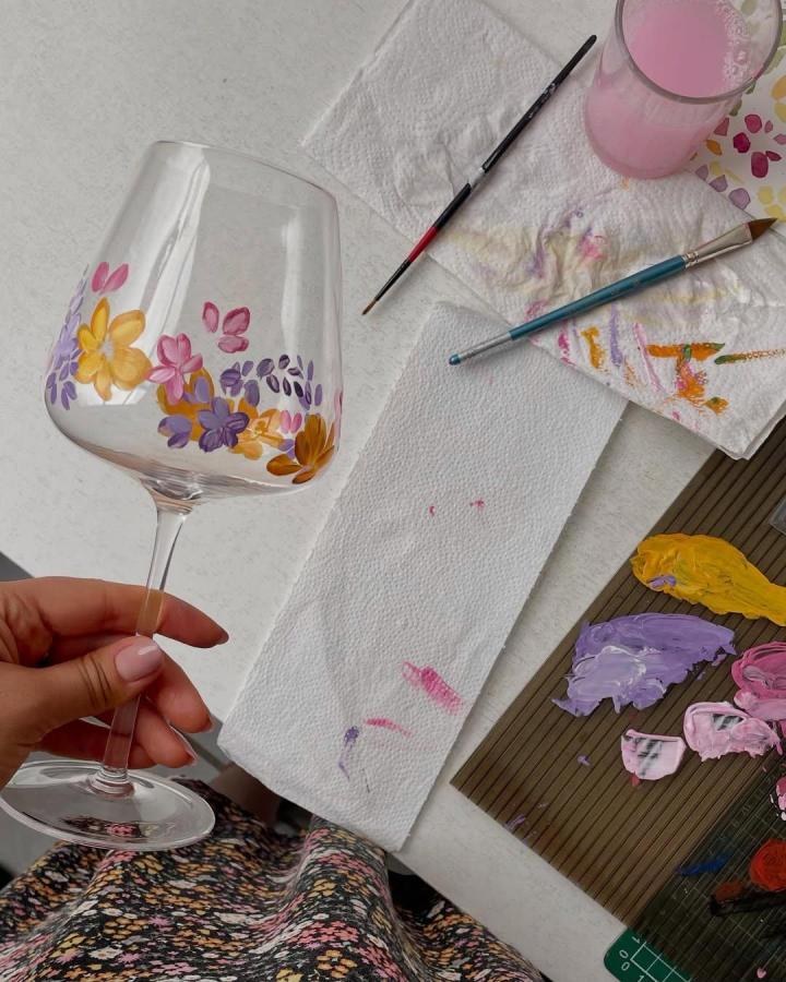 Hand painted wine glass with yellow pink and purple floral design from @lygiasalazart. Unique painting crafts for adults with delicate brushwork.
